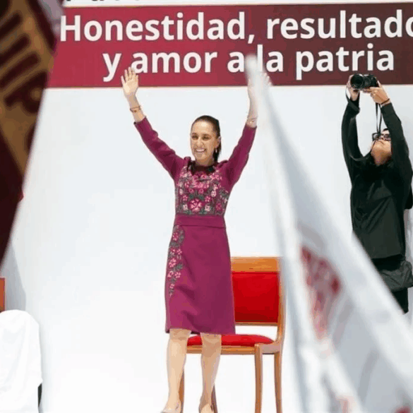 La presidenta Claudia Sheinbaum con los brazos en alto frente al lema Honestidad, resultados y amor a la patria durante su segundo informe de rendición de cuentas en el Monumento a la Revolución