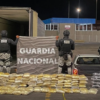 Elementos de la Guardia Nacional resguardan paquetes de droga decomisados junto a un tráiler durante un operativo nocturno.