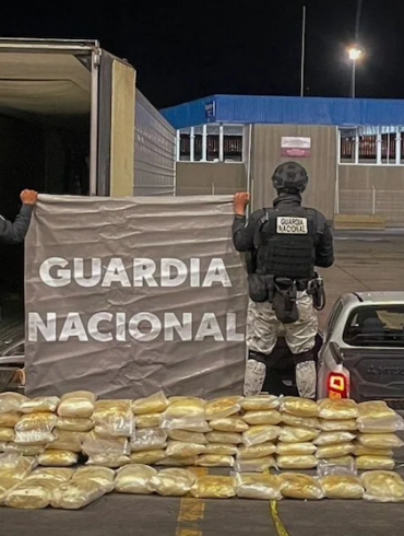 Elementos de la Guardia Nacional resguardan paquetes de droga decomisados junto a un tráiler durante un operativo nocturno.