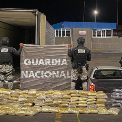 Elementos de la Guardia Nacional resguardan paquetes de droga decomisados junto a un tráiler durante un operativo nocturno.