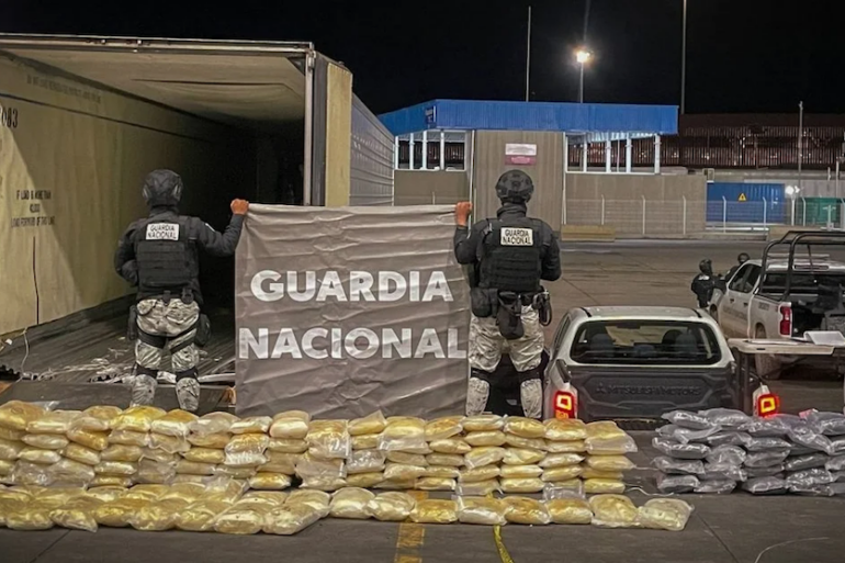 Elementos de la Guardia Nacional resguardan paquetes de droga decomisados junto a un tráiler durante un operativo nocturno.