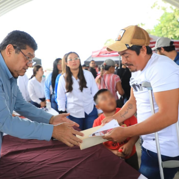 Autoridad estatal entrega documentos de apoyo a un beneficiario durante jornada social en Paraíso.