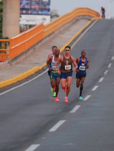 Corredores del Medio Maratón de Villahermosa avanzan por un puente urbano durante la prueba de 21 kilómetros.
