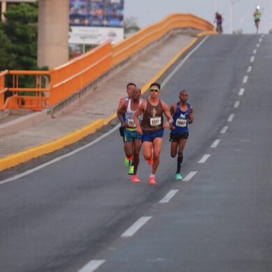 Corredores del Medio Maratón de Villahermosa avanzan por un puente urbano durante la prueba de 21 kilómetros.