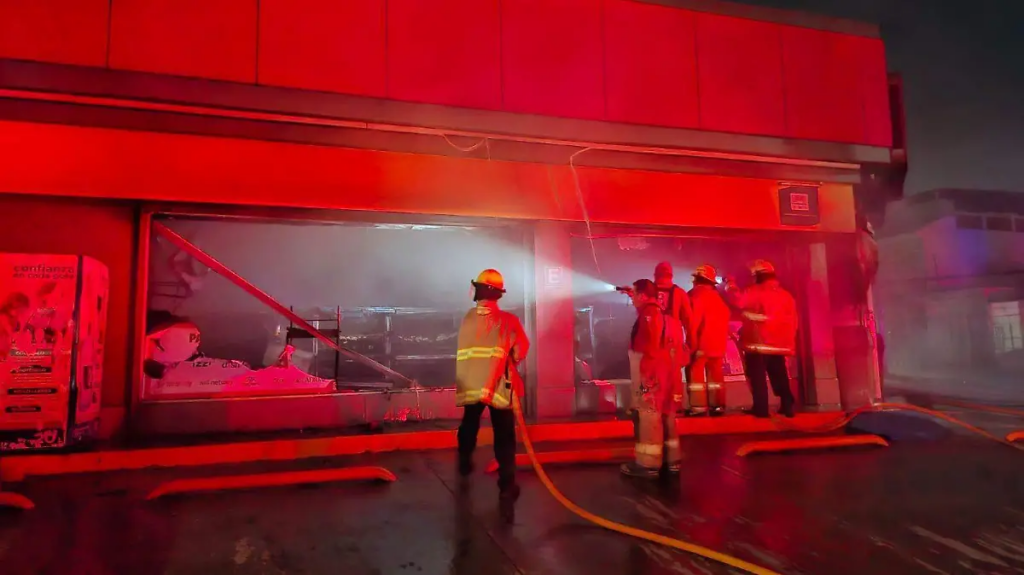 Bomberos inspeccionan una tienda de conveniencia incendiada durante los ataques registrados la noche del miércoles en Villahermosa.