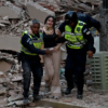 Mujer con collarín es auxiliada por policías entre escombros tras el terremoto en Venezuela.