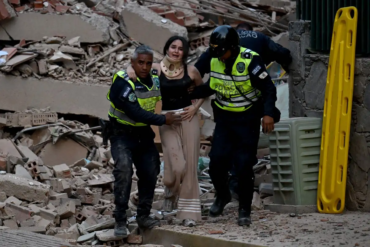 Mujer con collarín es auxiliada por policías entre escombros tras el terremoto en Venezuela.