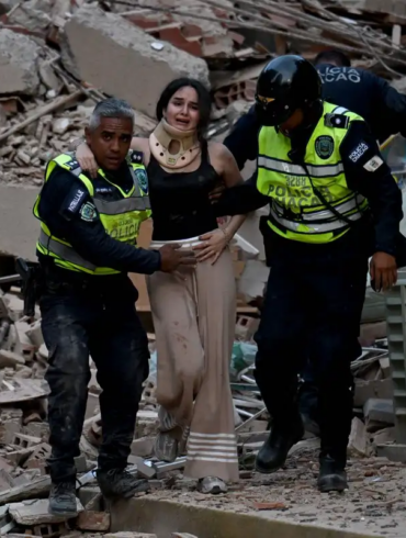 Mujer con collarín es auxiliada por policías entre escombros tras el terremoto en Venezuela.