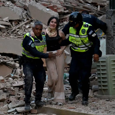 Mujer con collarín es auxiliada por policías entre escombros tras el terremoto en Venezuela.