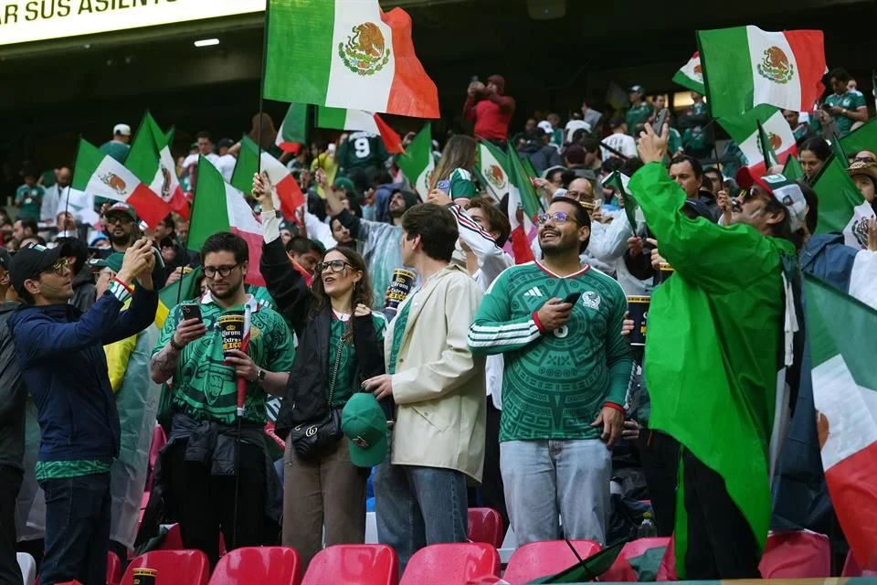 Aficionados de México celebran en las gradas con banderas nacionales y camisetas verdes.