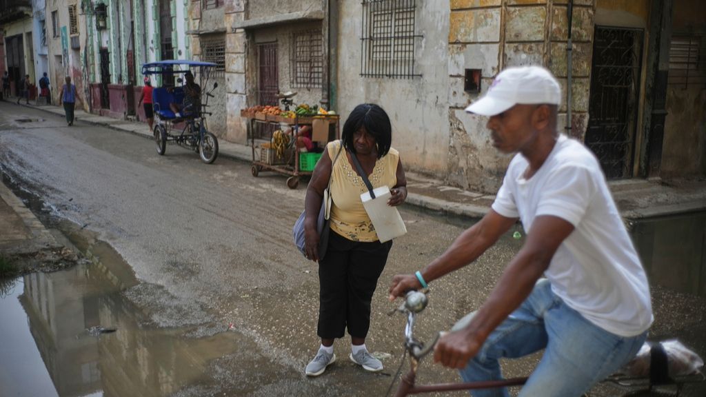 Habitantes de Cuba en una calle de La Habana con puesto de frutas y bicitaxi