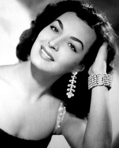 Elsa Aguirre, actriz mexicana de la Época de Oro, en retrato de estudio sonriendo con joyería de la época