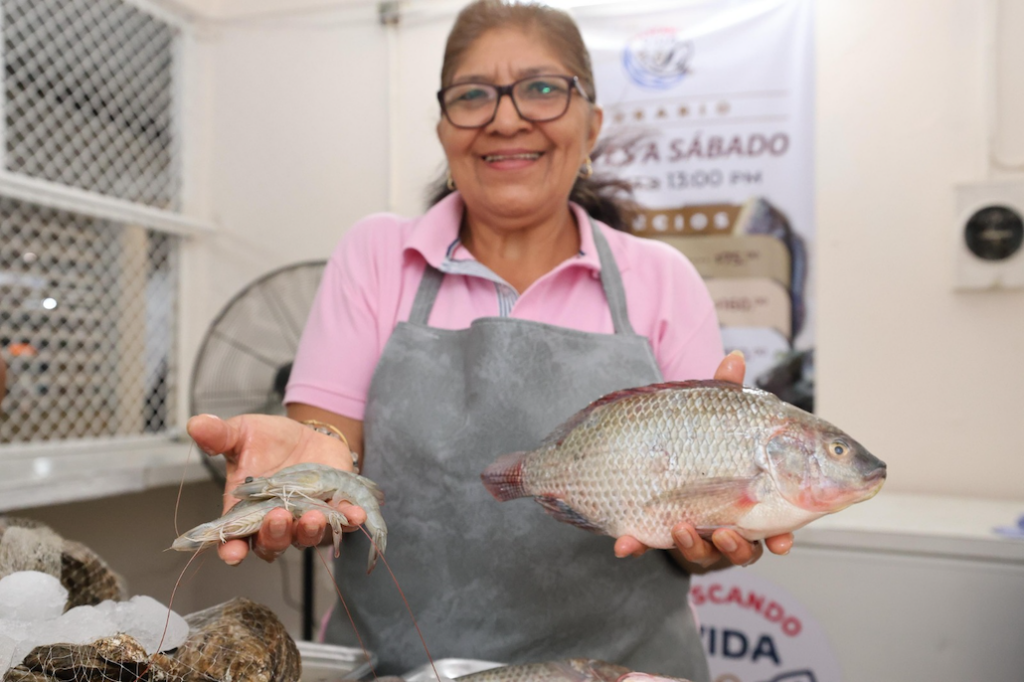 Vendedora muestra tilapia y camarón frescos en el nuevo punto de venta de Pescando Vida en Macuspana