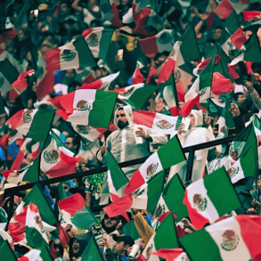 Aficionados mexicanos ondean banderas en una tribuna llena antes del partido contra Inglaterra.