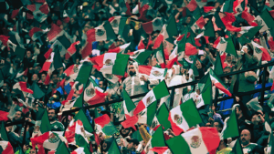 Aficionados mexicanos ondean banderas en una tribuna llena antes del partido contra Inglaterra.