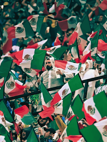 Aficionados mexicanos ondean banderas en una tribuna llena antes del partido contra Inglaterra.