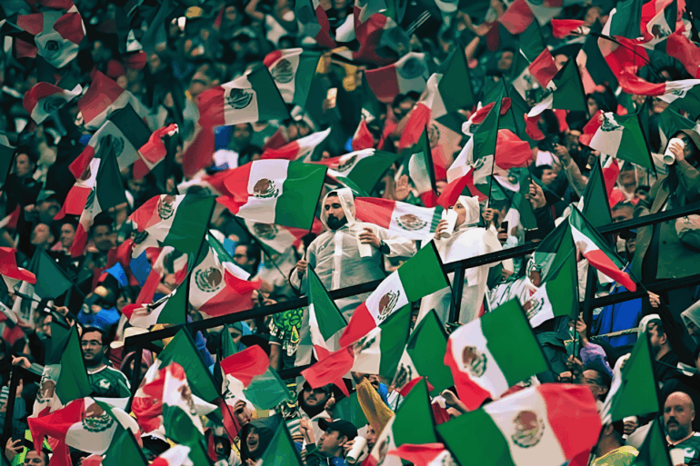 Aficionados mexicanos ondean banderas en una tribuna llena antes del partido contra Inglaterra.
