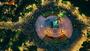 Vista aérea nocturna del Ángel de la Independencia rodeado por una multitud que celebra el pase de México a octavos de final del Mundial 2026