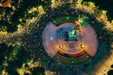 Vista aérea nocturna del Ángel de la Independencia rodeado por una multitud que celebra el pase de México a octavos de final del Mundial 2026