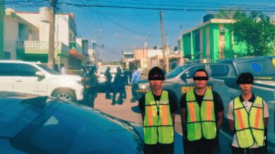 Tres personas detenidas con chalecos de identificación son presentadas por autoridades de Tabasco, con peritos y vehículos oficiales al fondo