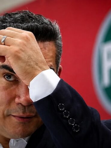 Alejandro Moreno, dirigente nacional del PRI, se lleva una mano a la frente frente al emblema de su partido.