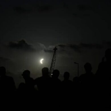 Siluetas de observadores contemplan una fase avanzada del eclipse solar de 2026 en la península ibérica.
