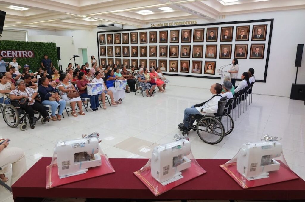 Mujeres beneficiarias reunidas en el Palacio Municipal de Centro durante la entrega de máquinas de coser, con la Galería de Ex-Presidentes al fondo