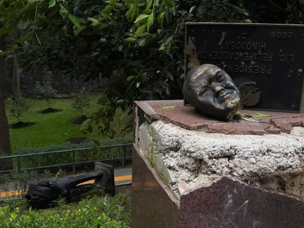 Cabeza de bronce de Felipe Calderón sobre el pedestal dañado en Los Pinos; al fondo, el cuerpo de la estatua tirado