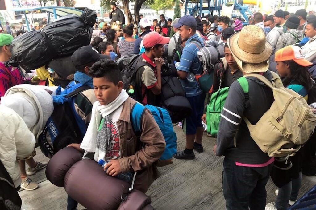 Migrantes centroamericanos esperan con mochilas y bultos durante el paso de una caravana rumbo al norte de México