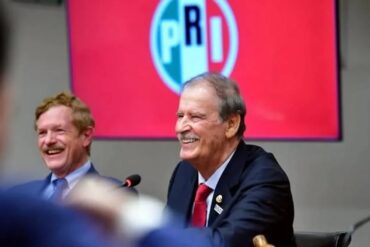 Vicente Fox sonríe durante su visita a la sede nacional del PRI, con el logotipo del partido de fondo