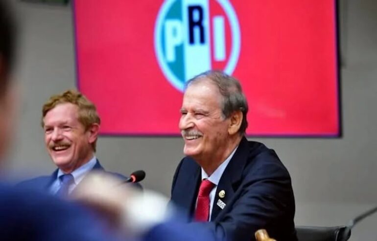 Vicente Fox sonríe durante su visita a la sede nacional del PRI, con el logotipo del partido de fondo
