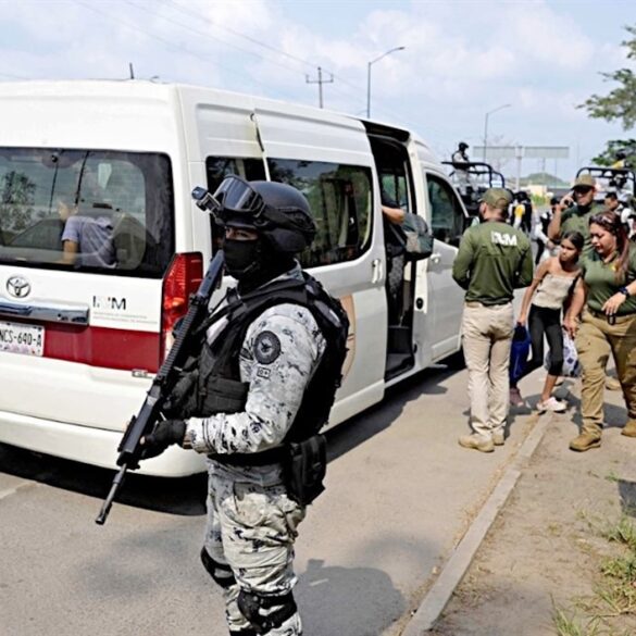 Elemento de la Guardia Nacional custodia el descenso de migrantes de una camioneta del INM en el sureste mexicano