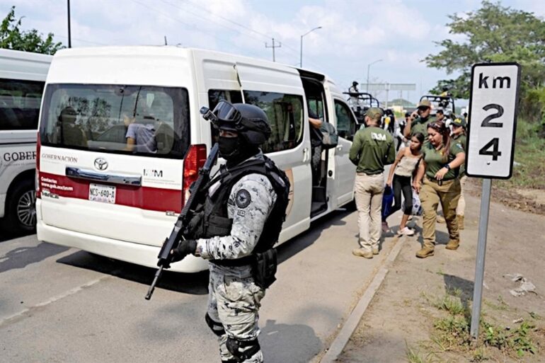 Elemento de la Guardia Nacional custodia el descenso de migrantes de una camioneta del INM en el sureste mexicano