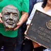 Manifestantes sostienen la cabeza de bronce de Felipe Calderón junto a la placa con la leyenda «Presidente Lic. Felipe Calderón Hinojosa 2006-2012»