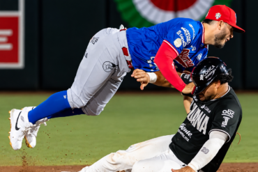 Jugador de Toros de Tijuana levanta los brazos mientras un pelotero de Olmecas aparece en primer plano.