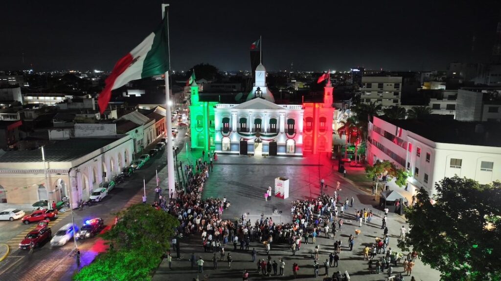 Vista aérea del Palacio de Gobierno de Tabasco iluminado y familias reunidas en Plaza de Armas