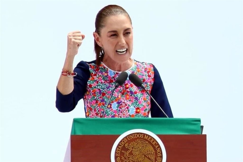 La presidenta Claudia Sheinbaum habla con el puño en alto detrás de un podio con el escudo nacional durante su mensaje de cierre de gira