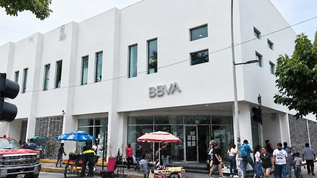 Personas reunidas frente al acceso principal de una sucursal de BBVA.