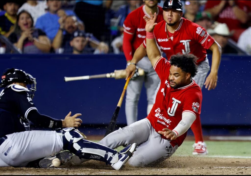 Jugador de Toros de Tijuana se barre en el plato mientras el receptor intenta completar la jugada.