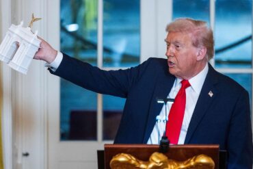 Donald Trump sostiene una maqueta del arco que planea construir entre el Monumento a Lincoln y el Cementerio de Arlington