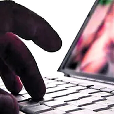 Mano sobre el teclado de una computadora portátil con una imagen desenfocada en pantalla, ilustración de los delitos sexuales digitales.