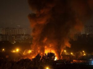 Incendio de grandes dimensiones ilumina la noche en una ciudad de Ucrania, con una enorme columna de humo junto a edificios residenciales.