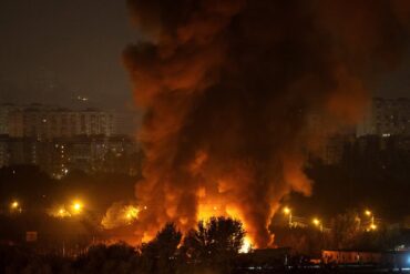 Incendio de grandes dimensiones ilumina la noche en una ciudad de Ucrania, con una enorme columna de humo junto a edificios residenciales.