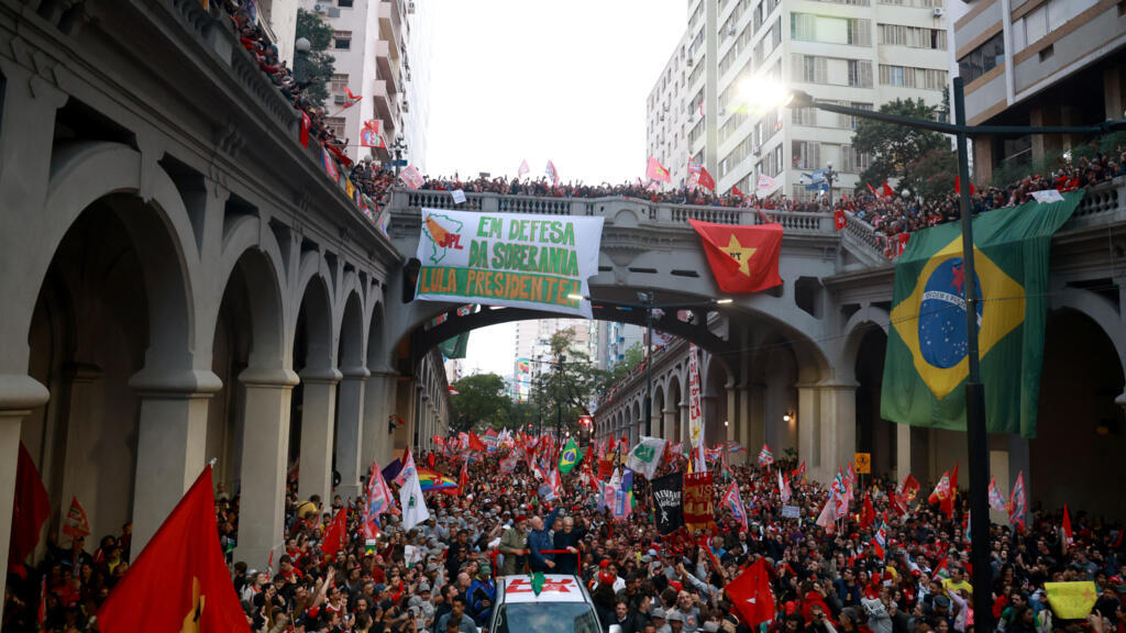 Multitud de simpatizantes de Lula da Silva marcha por una avenida de Brasil con banderas del Partido de los Trabajadores y una pancarta en defensa de su candidatura presidencial.