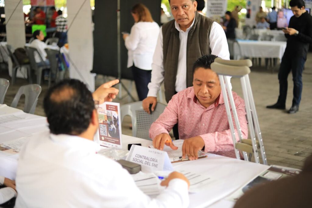 Personal de atención y personas solicitantes revisan documentos en una mesa de la feria de empleo celebrada en Comalcalco.