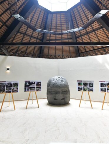 Cabeza colosal olmeca al centro de la sala de exhibición renovada del Parque Museo La Venta, con esculturas a los lados y paneles fotográficos