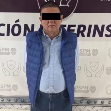Persona presentada como detenida, con chaleco azul y ojos cubiertos por una franja negra, ante un fondo institucional en Chihuahua.