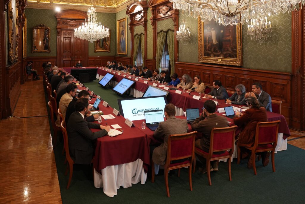 Vista panorámica de una reunión de autoridades federales y estatales alrededor de una mesa de trabajo en Palacio Nacional.