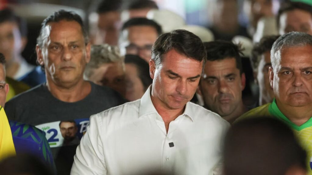 Flávio Bolsonaro, vestido con camisa blanca y rodeado de simpatizantes, durante la jornada electoral presidencial de Brasil en 2026.