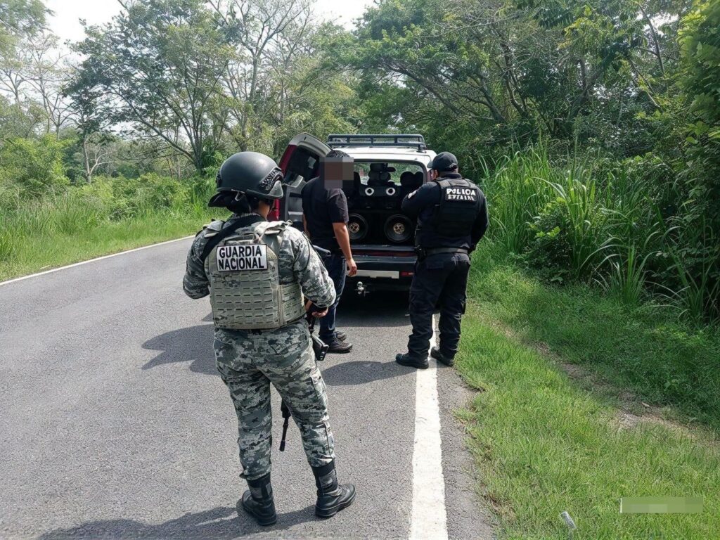 Elemento de la Guardia Nacional vigila la revisión de un hombre junto a una camioneta en una carretera de Tabasco